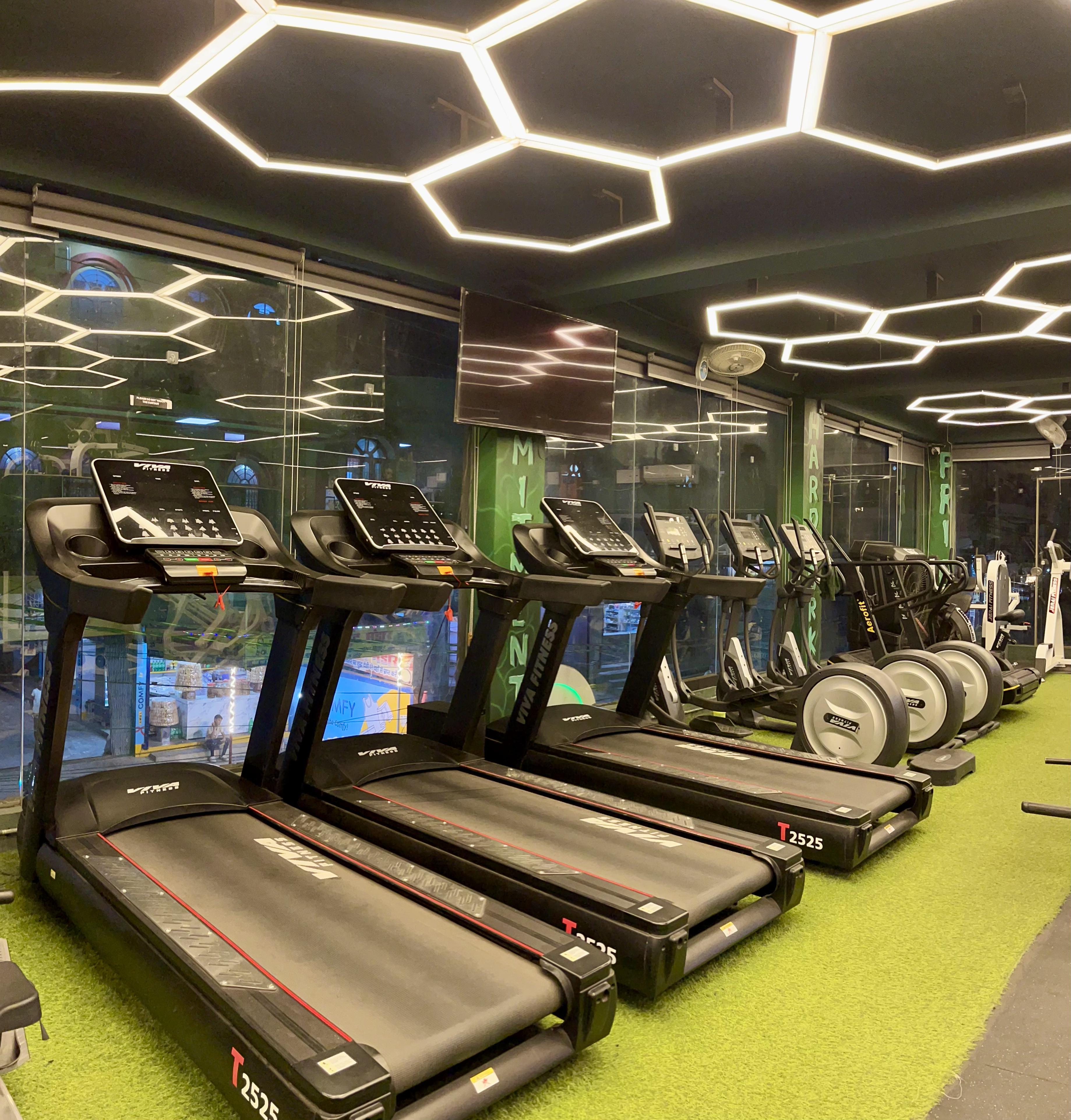 Row of treadmills with hexagonal LED ceiling at Hulk Fitness